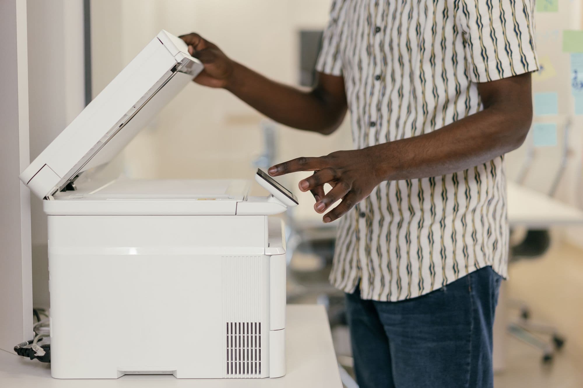 Person lifting the lid of a photocopier and pressing its touch panel